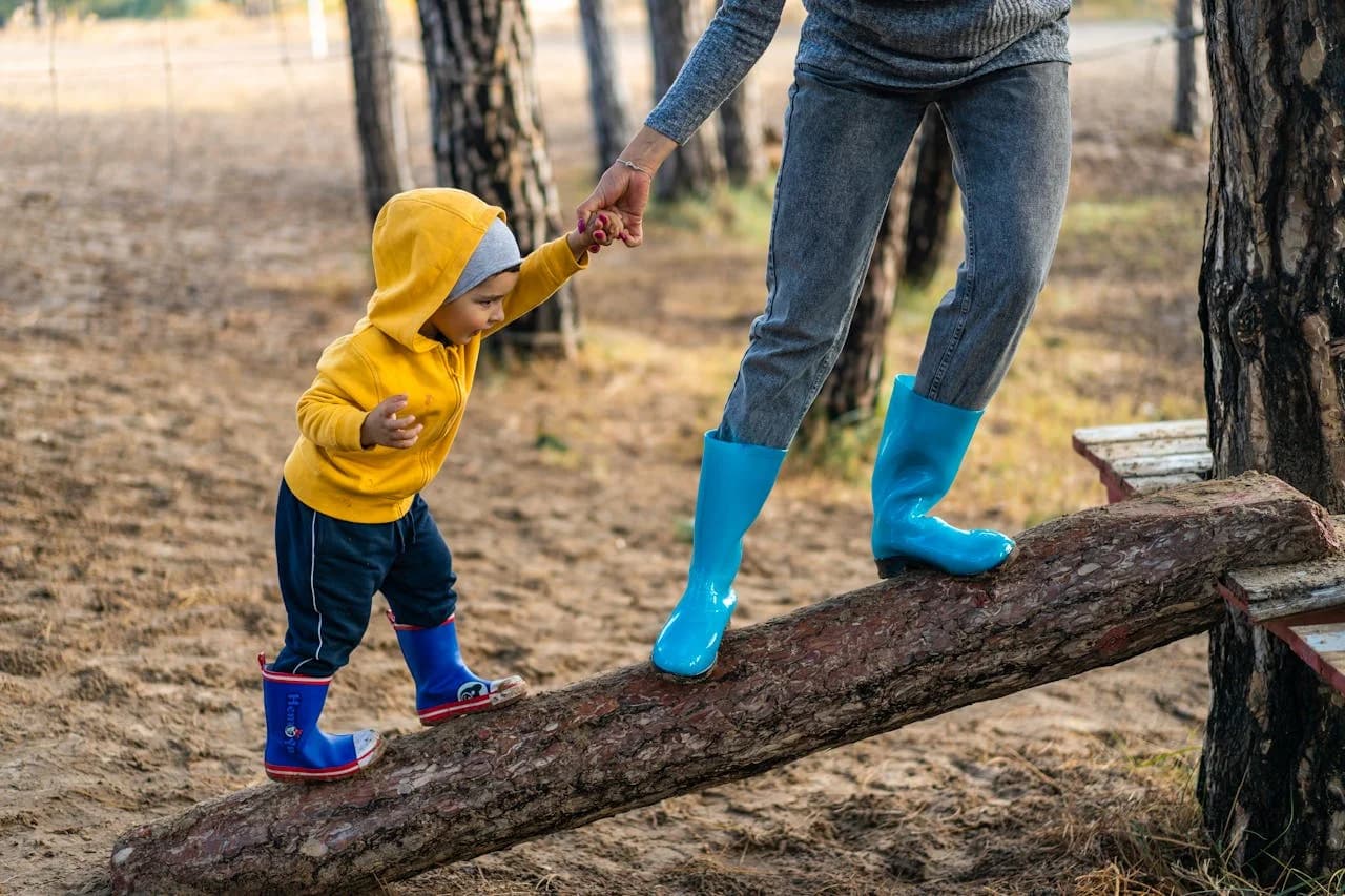 An adult helping a child walk on a log
